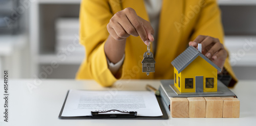 Real estate agent, african american businesswoman holding house model and keys with contract documents for buying or renting for clients in office.