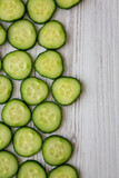 Sliced Organic Mini Baby Cucumbers on a white wooden background, top view. Flat lay, overhead, from above. Space for text.