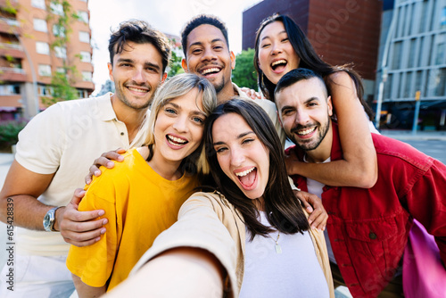 Diverse group of young people having fun taking selfie portrait together outside. Pretty woman smile at camera standing together with college student friends. Youth community and friendship concept.