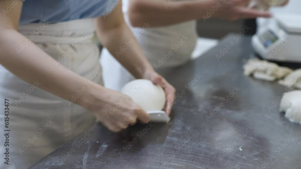 The female hands of the bakery workers separate portions of the dough to be weighed on the scales for making bread. Craft bakery. Production of tasty and healthy bread The female hands of the bakery workers separate portions of the dough to be weighed on the scales for making bread. Craft bakery. Production of tasty and healthy bread