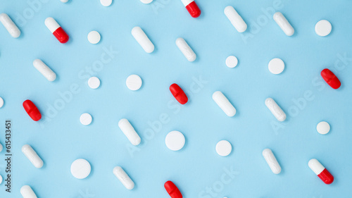 Various colorful medication tablets and capsules on blue background. Concept of healthcare and medicine. Top view, pattern