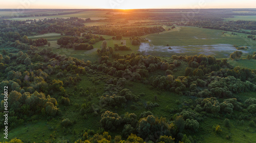 Aerial view beautiful landscape at sunset or sunrise in summer. Drone flying over field in sunny day. Drone shot nature and forest