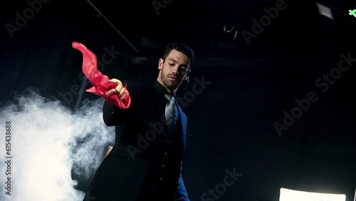 Magician doing magic tricks with a red and a white handkerchief. Mysterious background with smoke.