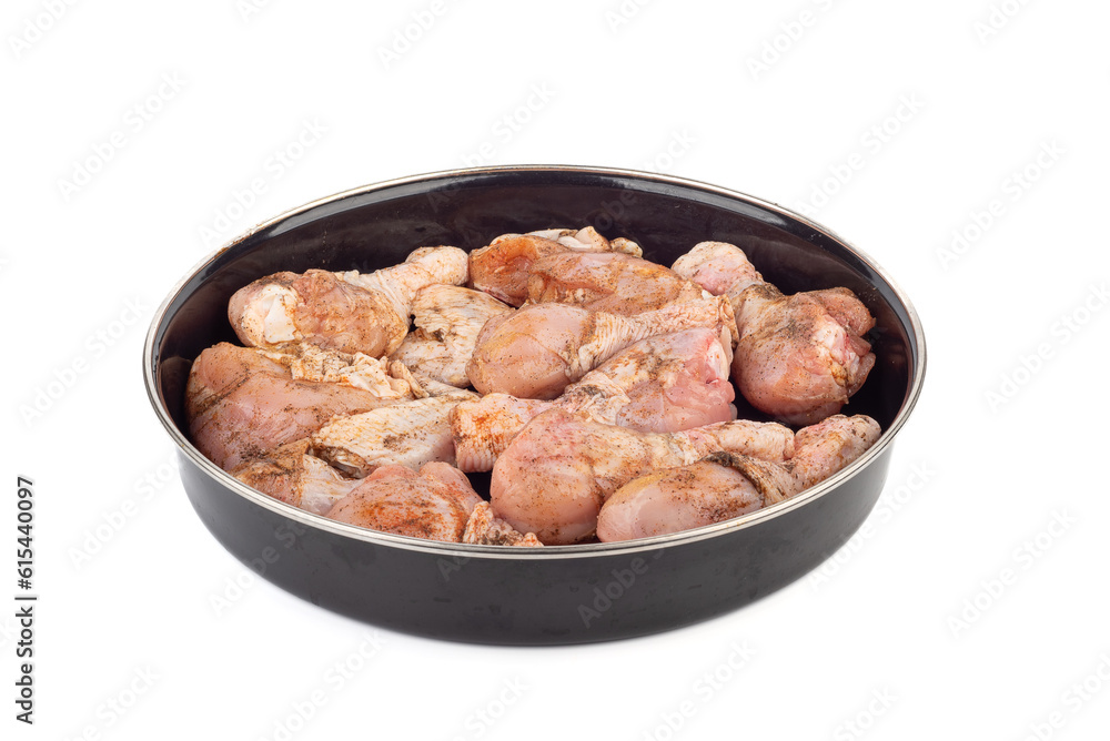 Ready-to-bake chicken drumsticks in a round metal mold over a white background.