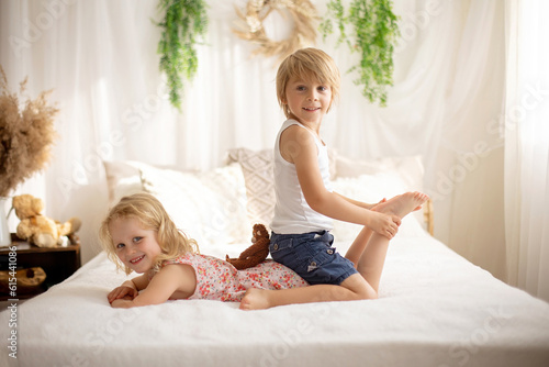Картината върху платно Cute sweet toddler children, tickling feet on the bed, laughing and smiling