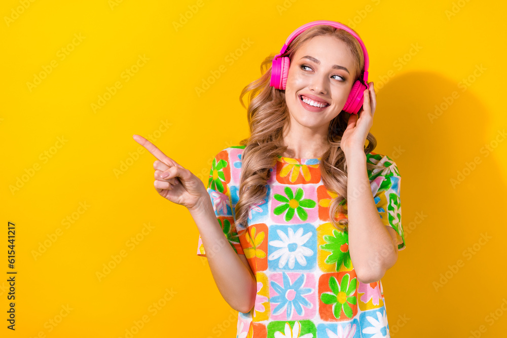 Photo of cheerful optimistic girl dressed colorful t-shirt look directing at playlist empty space isolated on yellow color background Photo of cheerful optimistic girl dressed colorful t-shirt look directing at playlist empty space isolated on yellow color background