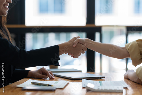 Two asian businesswoman shaking hands in modern office after success in financial business Documents investing in teamwork and friendship. startup business ideas real estate project.