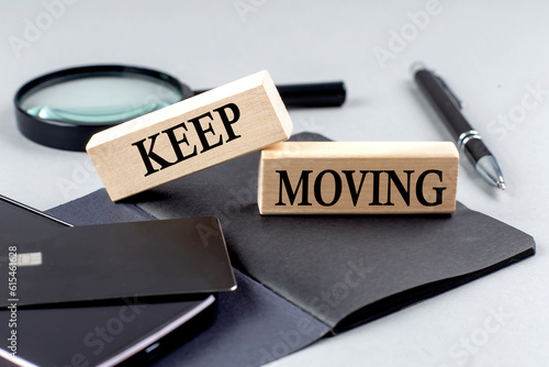 KEEP MOVING text on wooden block on black notebook , business concept