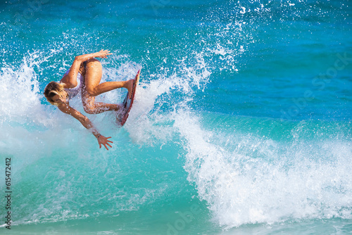 Skimboarder riding an ocean wave; Sandy Beach, Oahu, Hawaii, United States of America photo