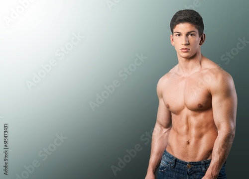 Muscular sporty young guy posing on background.