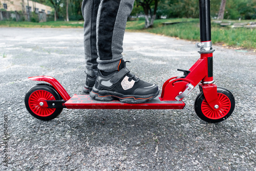 Children's red scooter is ready to ride. Red scooter on asphalt