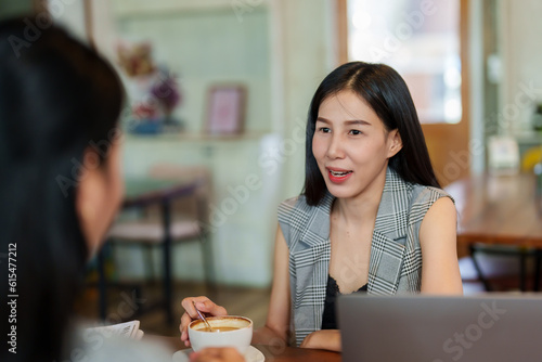 Two Asian women working in a cafe. Talk and consult about the work that is being done. and his hand was stirring the coffee in the cup, on a leisurely day