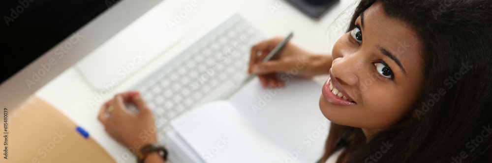 Smiling African American woman takes notes and writes in notebook. Confident business woman planning meeting work day and writing down ideas or important information Smiling African American woman takes notes and writes in notebook. Confident business woman planning meeting work day and writing down ideas or important information