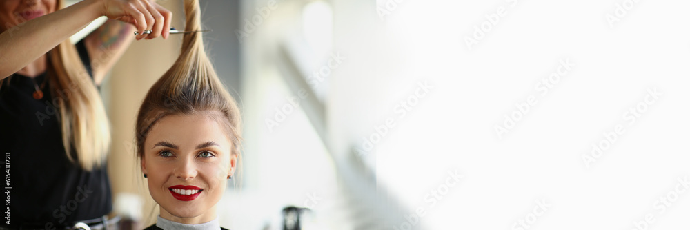 Fototapeta premium Hairdresser hands cut off blonde tail closeup. Woman hairdresser cutting long blond hair with scissors in barbershop