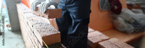 Photography Closeup of industrial bricklayer laying bricks at construction site
