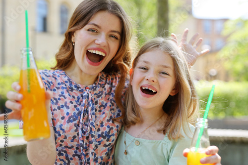 Happy woman and little girl with soda in their hands on a summer day. photo
