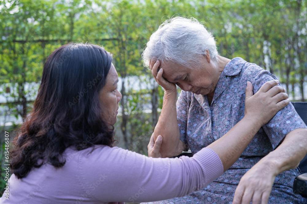 Asian elderly woman headache while sitting on wheelchair at park, healthy strong medical concept.