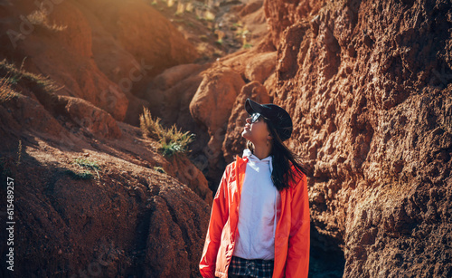 Portrait of impressed woman tourist walking in red sandstone canyon. Young female hiker in mountain trekking. Adventure, wanderlust, sightseeing.