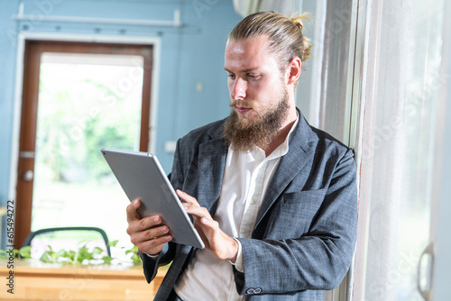 Bearded businessman hipster working standing crossed arms resting eyes by window looking at garden during lunch time standing at office