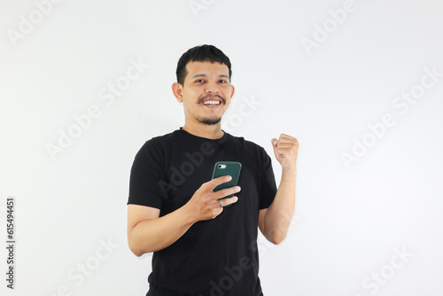 Adult Asian man holding mobile phone showing enthusiastic expression