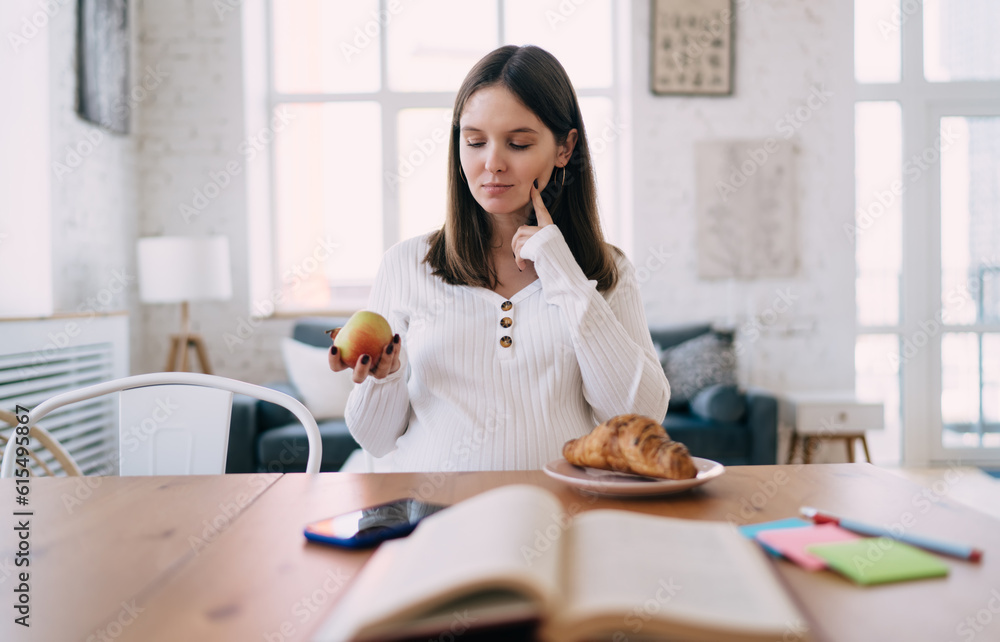Smiling pregnant woman choosing apple instead of croissant Smiling pregnant woman choosing apple instead of croissant