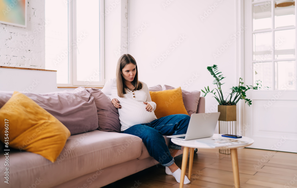 Pregnant woman having video conversation on computer touching belly breathing Pregnant woman having video conversation on computer touching belly breathing
