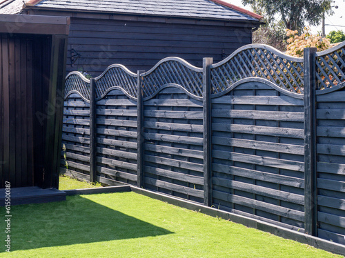 Wooden fence, painted black with fancy curving trellis on top