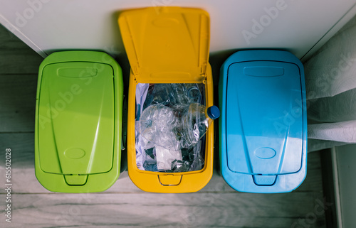 Top view of recycling containers and plastic bottles inside opened yellow recycling trash