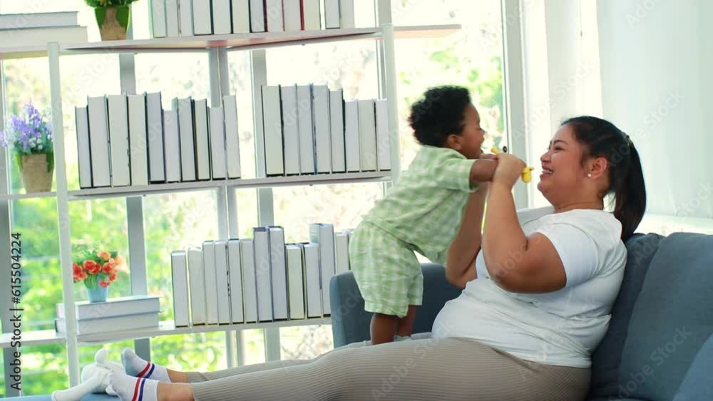 Asian mom sitting on sofa playing with cute son in living room : Thai mother raises a lovely 10 month old son of Thai African American Nigerian descent with love. Asian mom sitting on sofa playing with cute son in living room : Thai mother raises a lovely 10 month old son of Thai African American Nigerian descent with love.