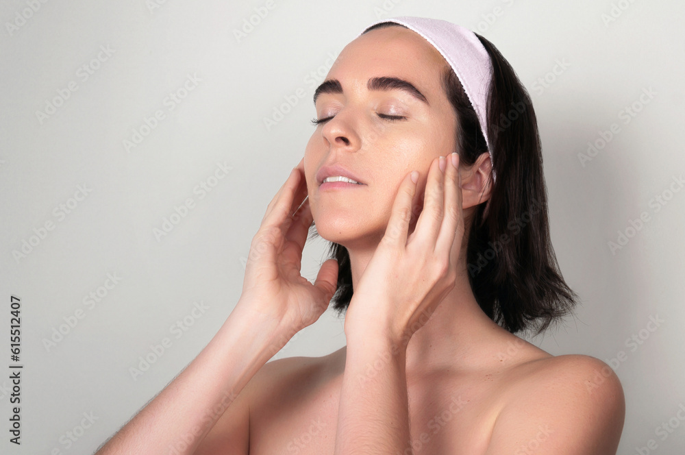 Young woman with headband standing and touching face with fingers Young woman with headband standing and touching face with fingers