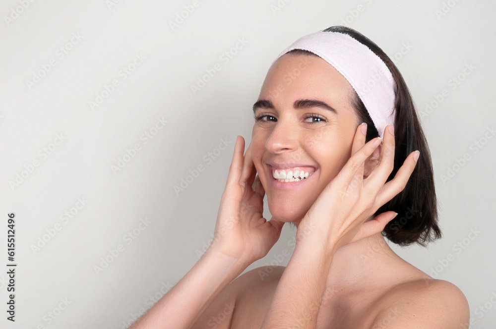 Happy young woman with headband standing and touching face with fingers Happy young woman with headband standing and touching face with fingers