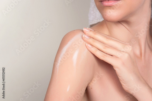 Crop anonymous woman applying moisturizing cream on shoulder