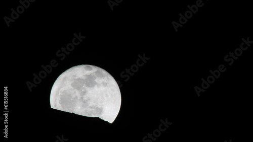 moon rising behind a rock