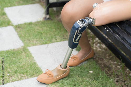 Amputated woman. Female with prosthetic leg sitting outdoor in the garden. Woman handicapper with prosthetic leg. Asian woman with leg prosthesis equipment outdoor photo