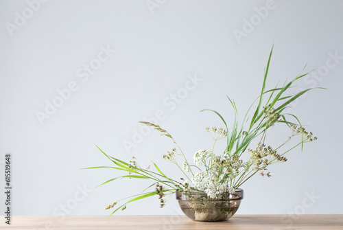 arrangement of wild flowers and plants in  glass bowl on  gray background