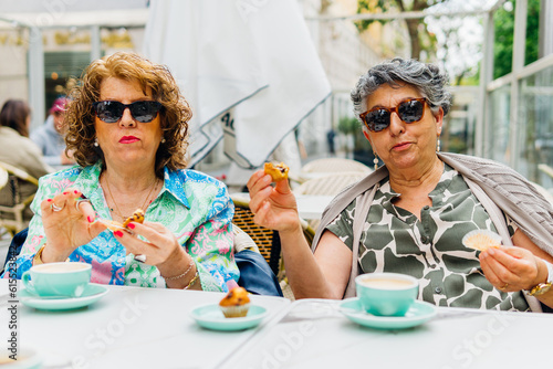 Positive middle age women with desserts in outdoor cafe © Dani D.G