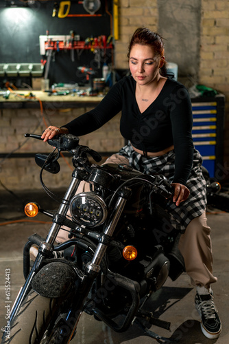 Creative authentic motorcycle workshop garage beautiful young girl biker sitting on a cool motorcycle © Guys Who Shoot