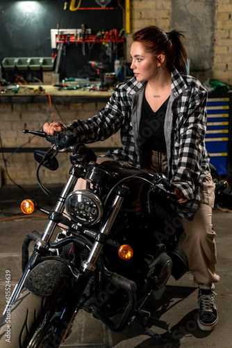 Creative authentic motorcycle workshop garage beautiful young girl biker sitting on a cool motorcycle © Guys Who Shoot