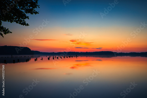 See im Abendrot - Sunset - Landscape - Beautiful Sunset scene over the lake and silhouette hills in the background - Sunrise over sea - Colorful - Reed - Clouds - Sky - Sundown - Sun © Enrico Obergefäll