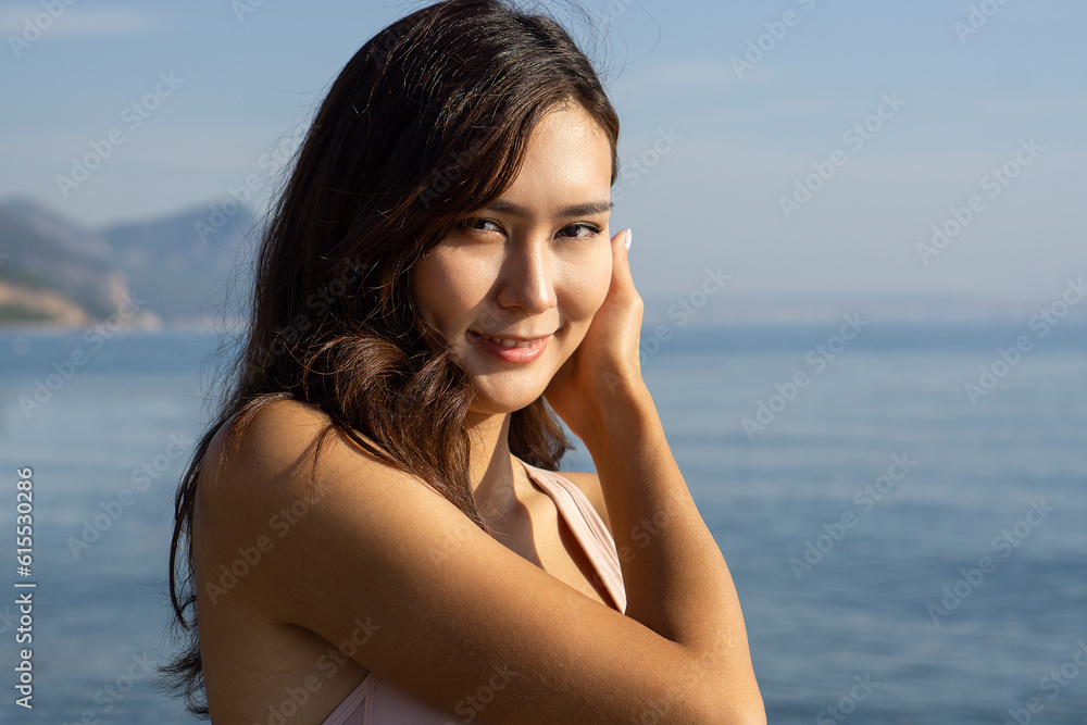 Charming happy Asian woman smiling at camera while standing in front of amazing mountain landscape Charming happy Asian woman smiling at camera while standing in front of amazing mountain landscape