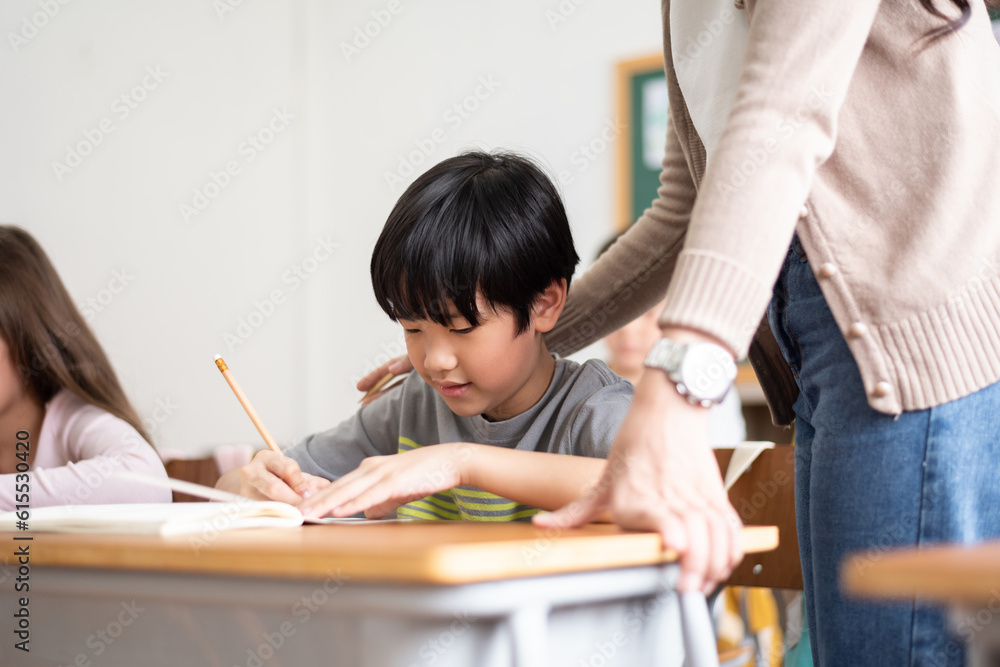 Asian Japanese boy writing at desk in classroom at Elementary school. Asian Japanese boy writing at desk in classroom at Elementary school.