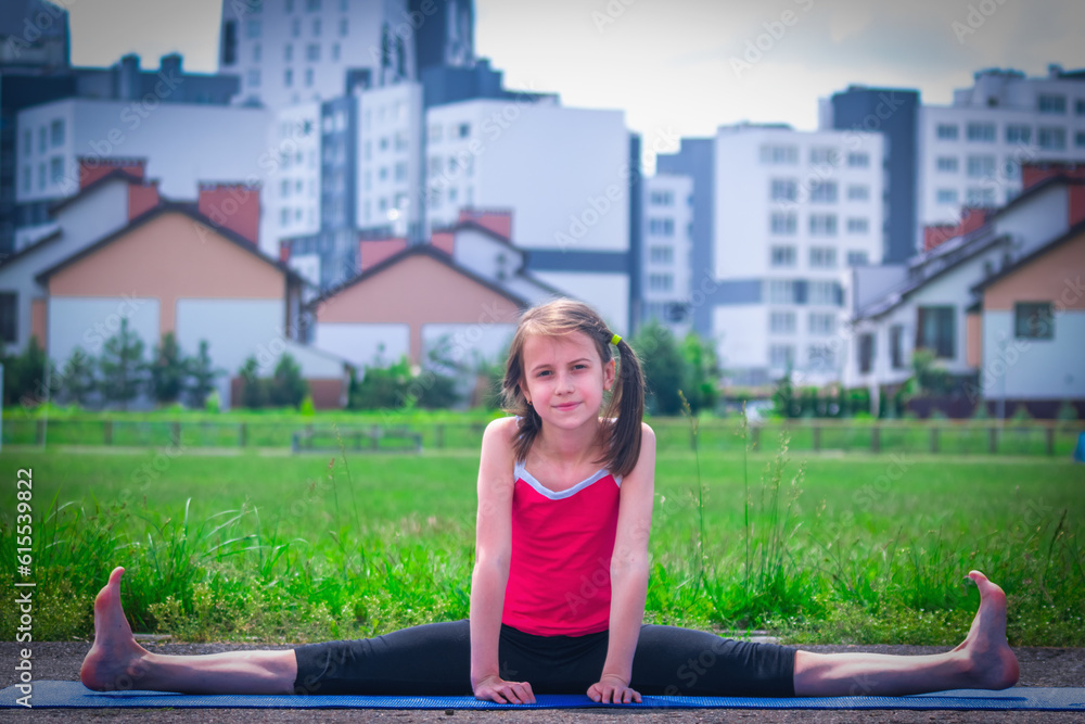 Fototapeta premium Young sporty attractive girl doing warmup exercise and stretch her legs. Sports training in urban conditions.