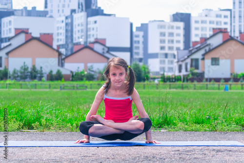 Portrait of young sporty attractive girl doing yoga exercise on blue mat, arm balance exercise with crossed legs, Scale Posture, Tolasana, Utpluthi Pose, full length photo