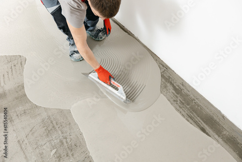 Leveling with mixture of cement for floors. Worker use screed concrete epoxy for level