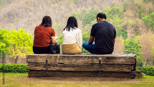 Back view of Asian family relaxing near mountain. Relax lifestyle for people enjoying freedom in summer holidays. Happy family outdoors resting together. Enjoying nature outdoors with mountain view.