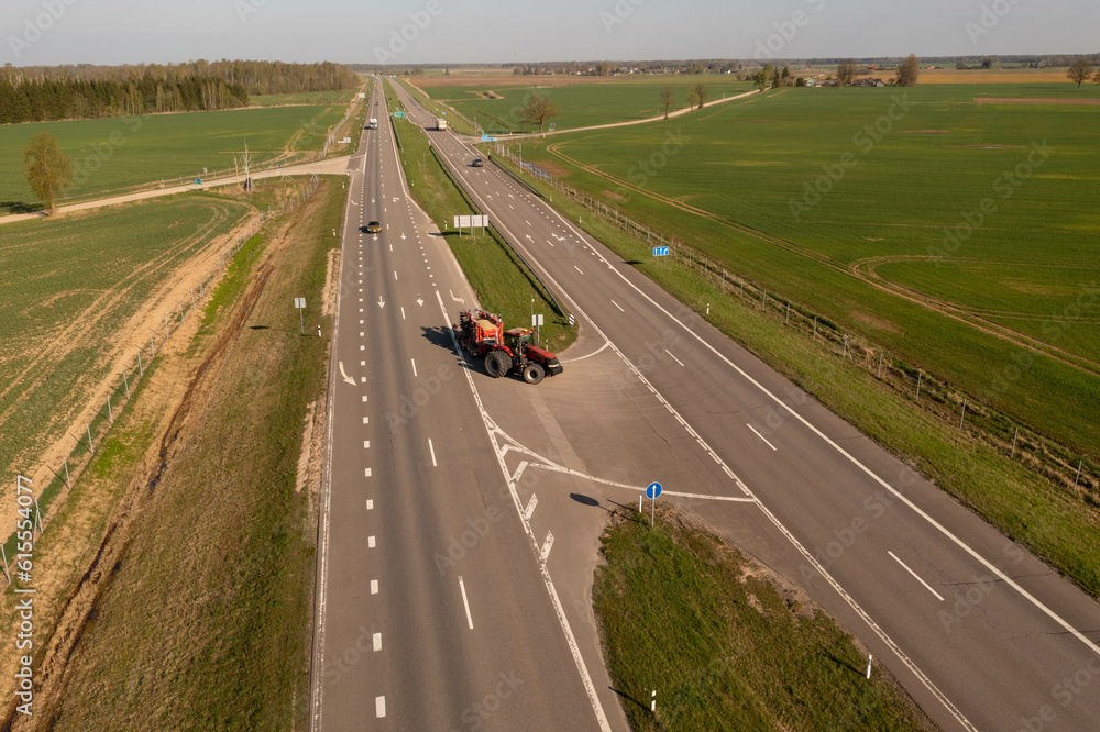 Drone photography of tractor with agricultural equipment driving on a road Drone photography of tractor with agricultural equipment driving on a road