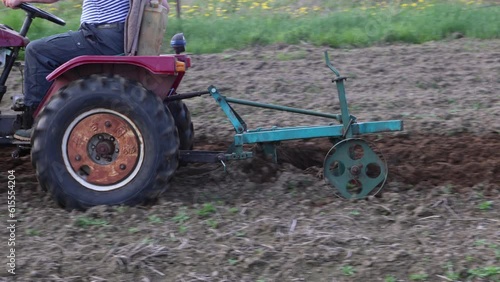 Mini tractor with plow cultivates soil in potato field. photo