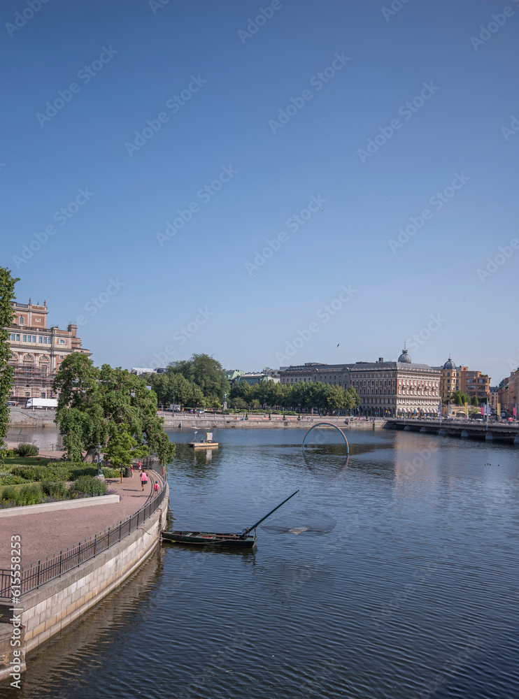 Stone parterre, round net fishing boat, piers and bridge at the bay Strömmen, a sunny summer day in Stockholm Stone parterre, round net fishing boat, piers and bridge at the bay Strömmen, a sunny summer day in Stockholm