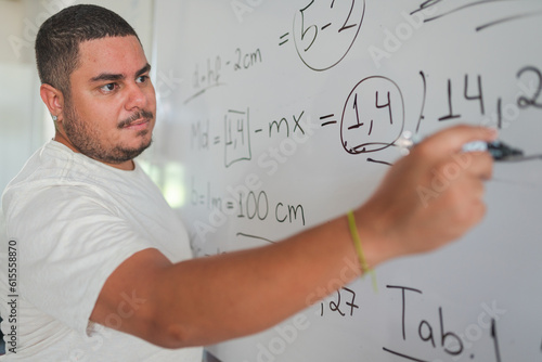 Brazilian student of an adult class solving the math activity given by the teacher on the blackboard in a college in Latin America