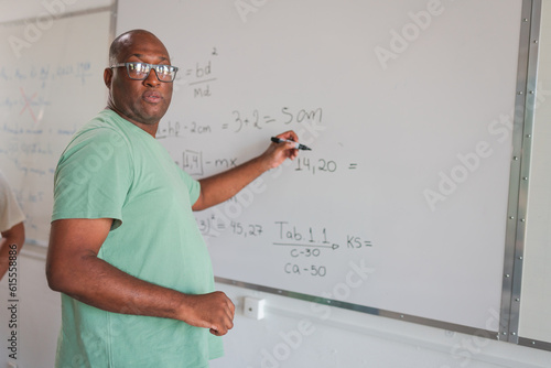 estudante Brasileiro negro careca resolvendo na lousa o problema de matemática passado pelo professor eu um curso para adultos no Brasil